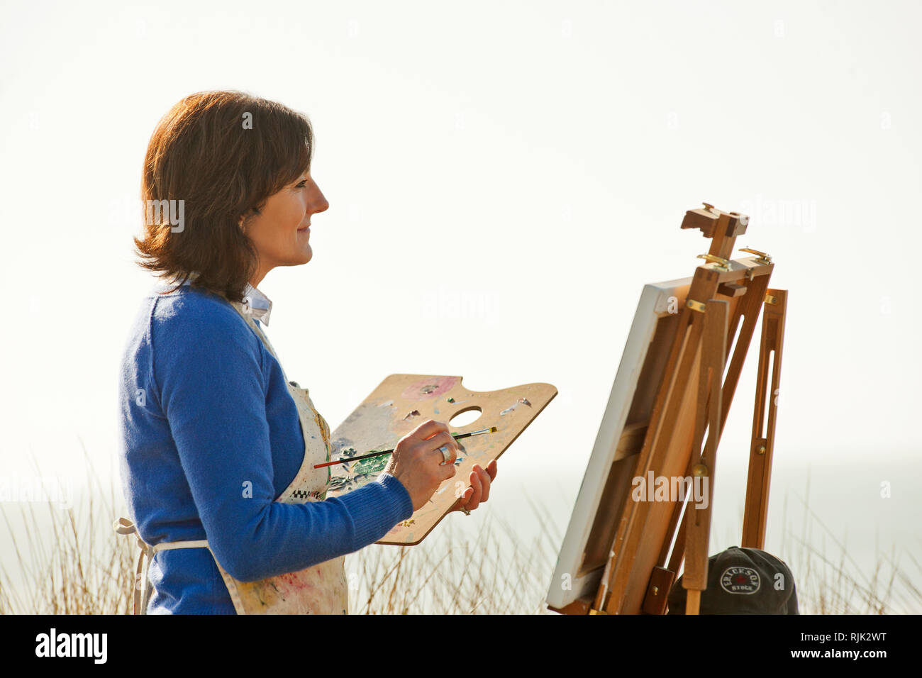 Gerne reife Frau malen ein Bild von einem malerischen Blick auf den Strand. Stockfoto