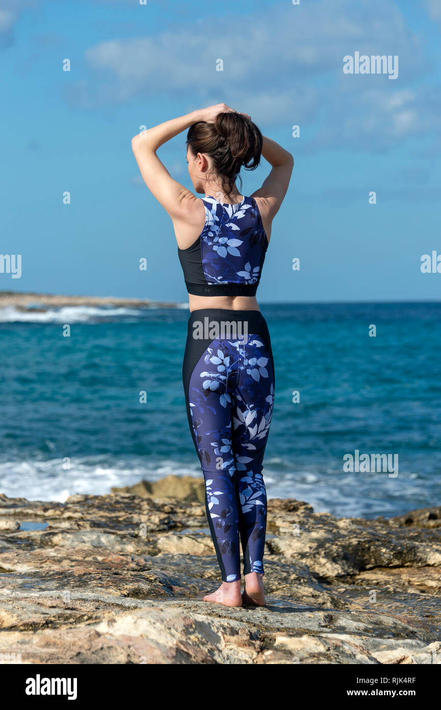 Sport Frau binden ihr Haar, Vorbereitung und Übung am Meer in der Sonne Stockfoto