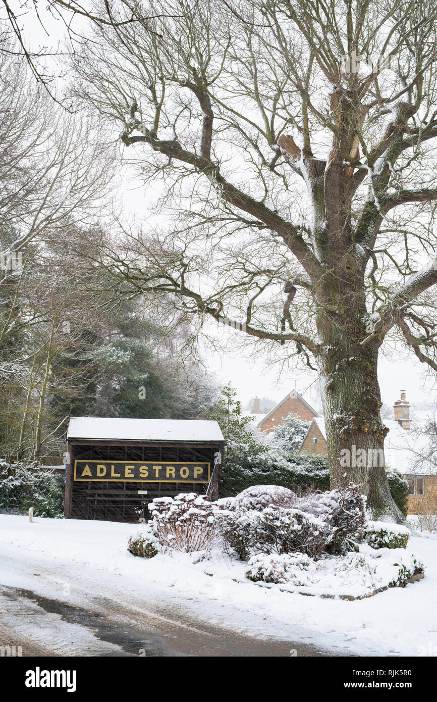 Adlestrop Ortsschild und Bushaltestelle im Winter Schnee. Adlestrop, Cotswolds, Gloucestershire, England Stockfoto