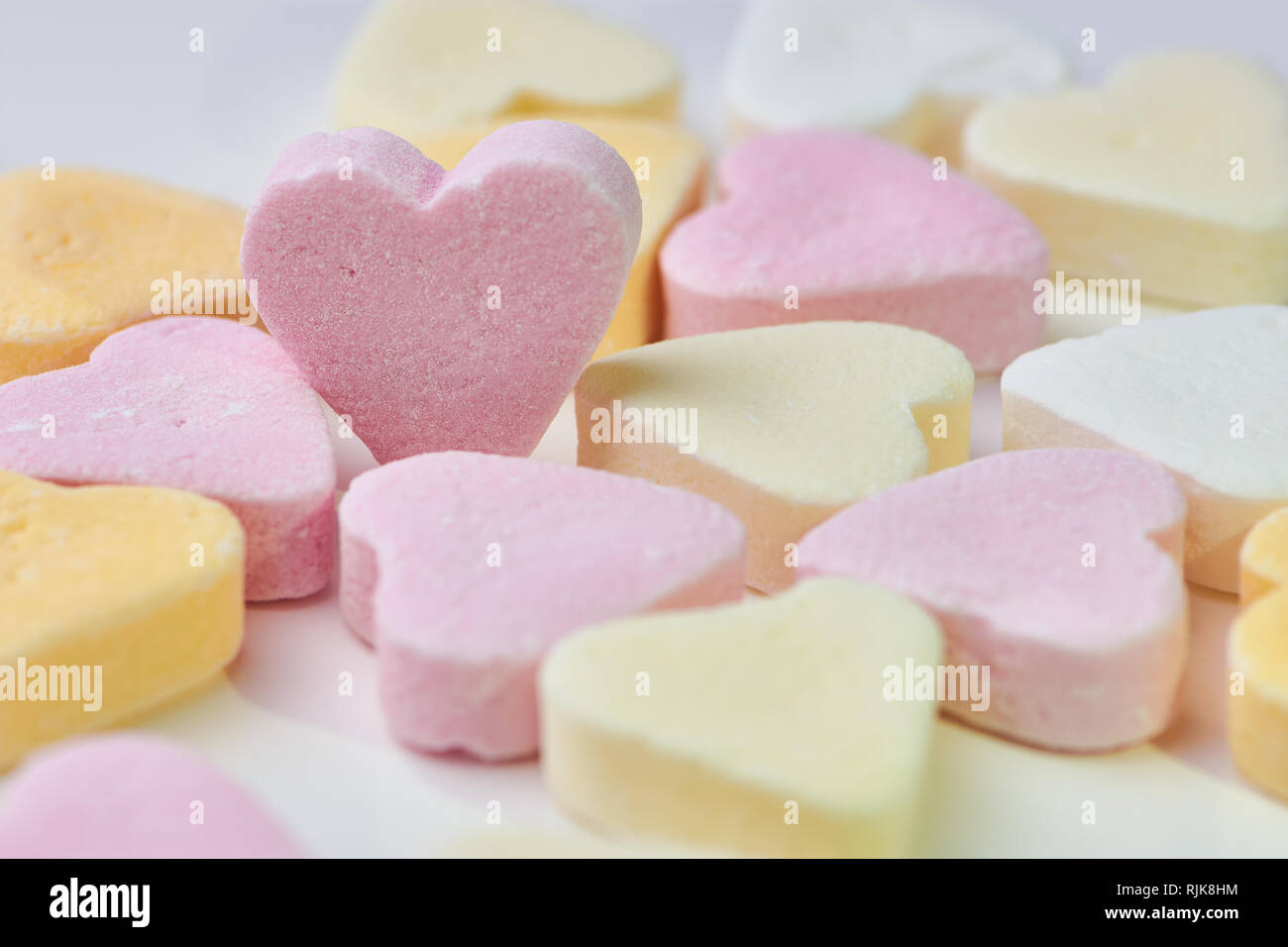 Makro Farbe Foto von Candy Herzen liegen auf weißem Hintergrund, ein rosa Herz steht, Platz kopieren Stockfoto
