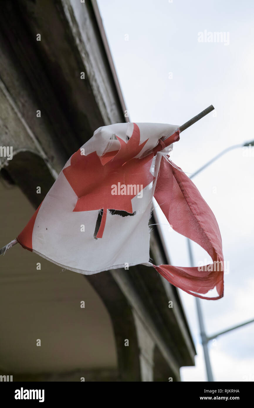 Ein abgenutzter und zerrissen kleinen Kanadischen Flagge, Leider hängen an der Seite eines historischen Gebäudes. Stockfoto