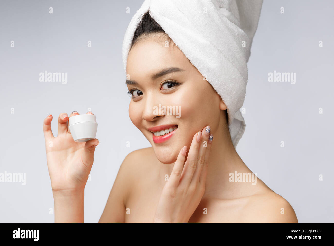 Gesundheit und Schönheit Konzept - Attraktive asiatische Frau Anwendung der Creme auf der Haut, isoliert auf Weiss. Stockfoto