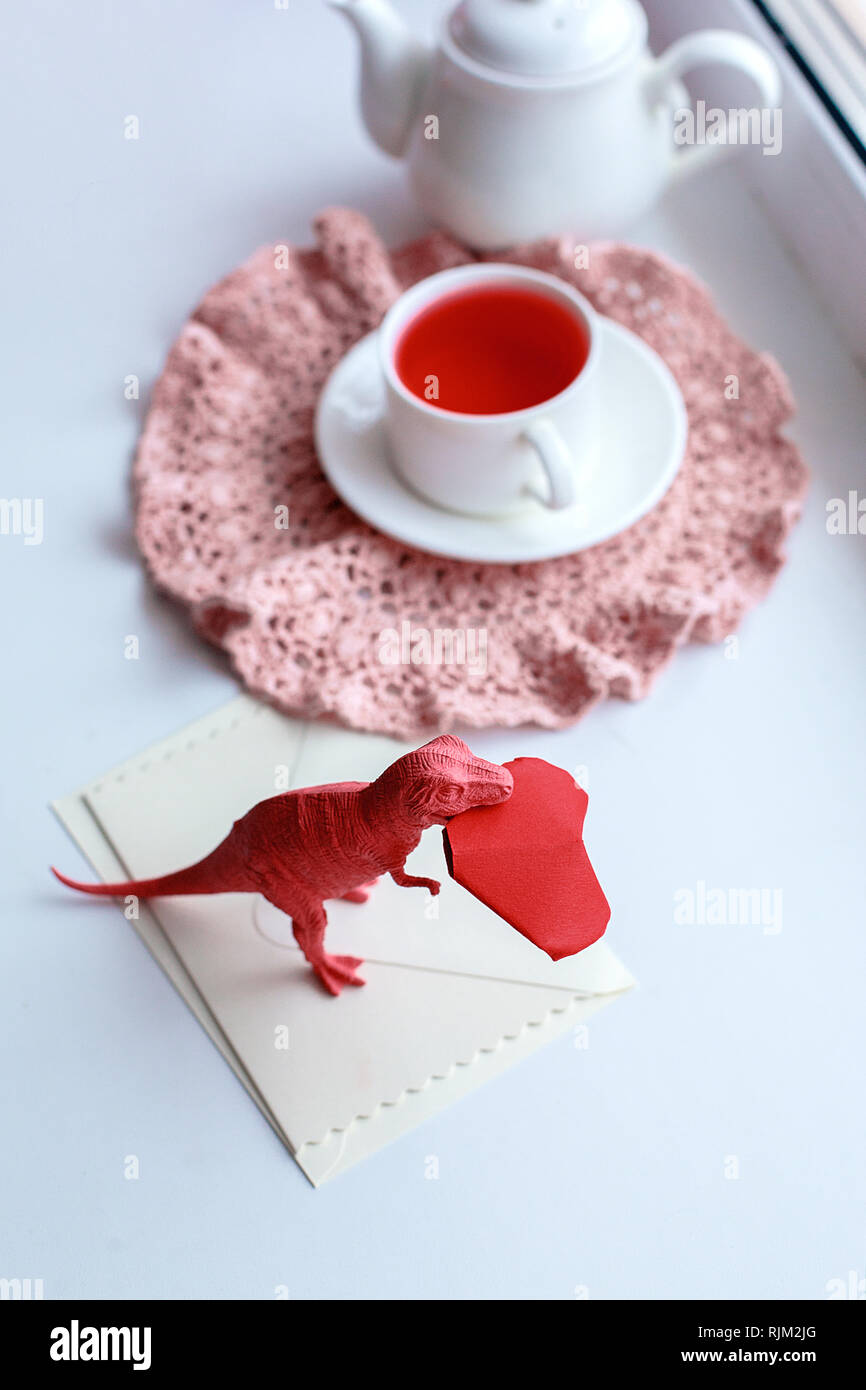 Spielzeug dinosuar beißen Paper Craft origami rotes Herz, surreale trendige Konzept der Valentines Tag, lebende Korallen Farbe Stockfoto