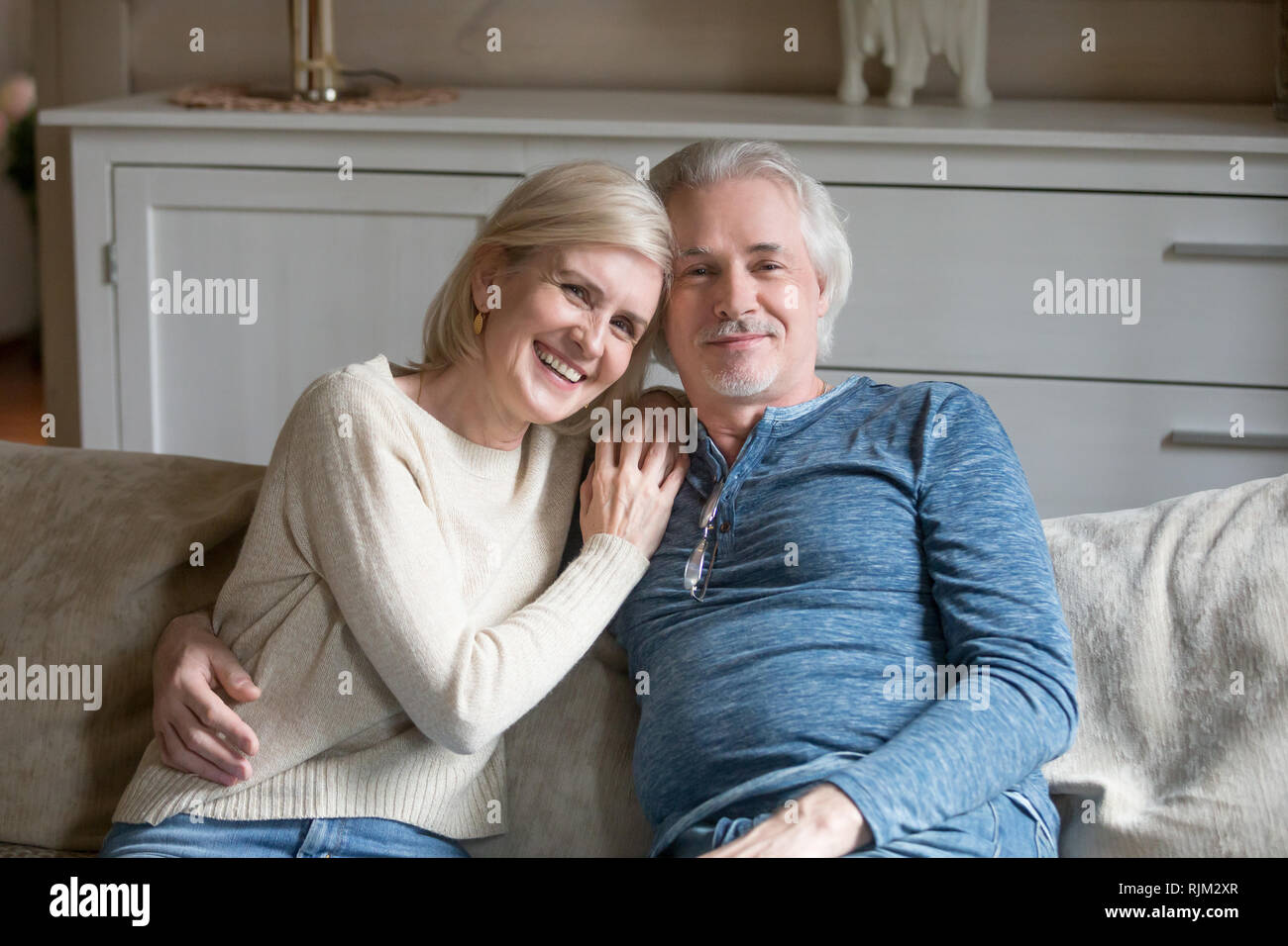 Wohlbefinden im Alter zwischen Ehegatten sitzen auf einem Sofa an Kamera suchen Stockfoto