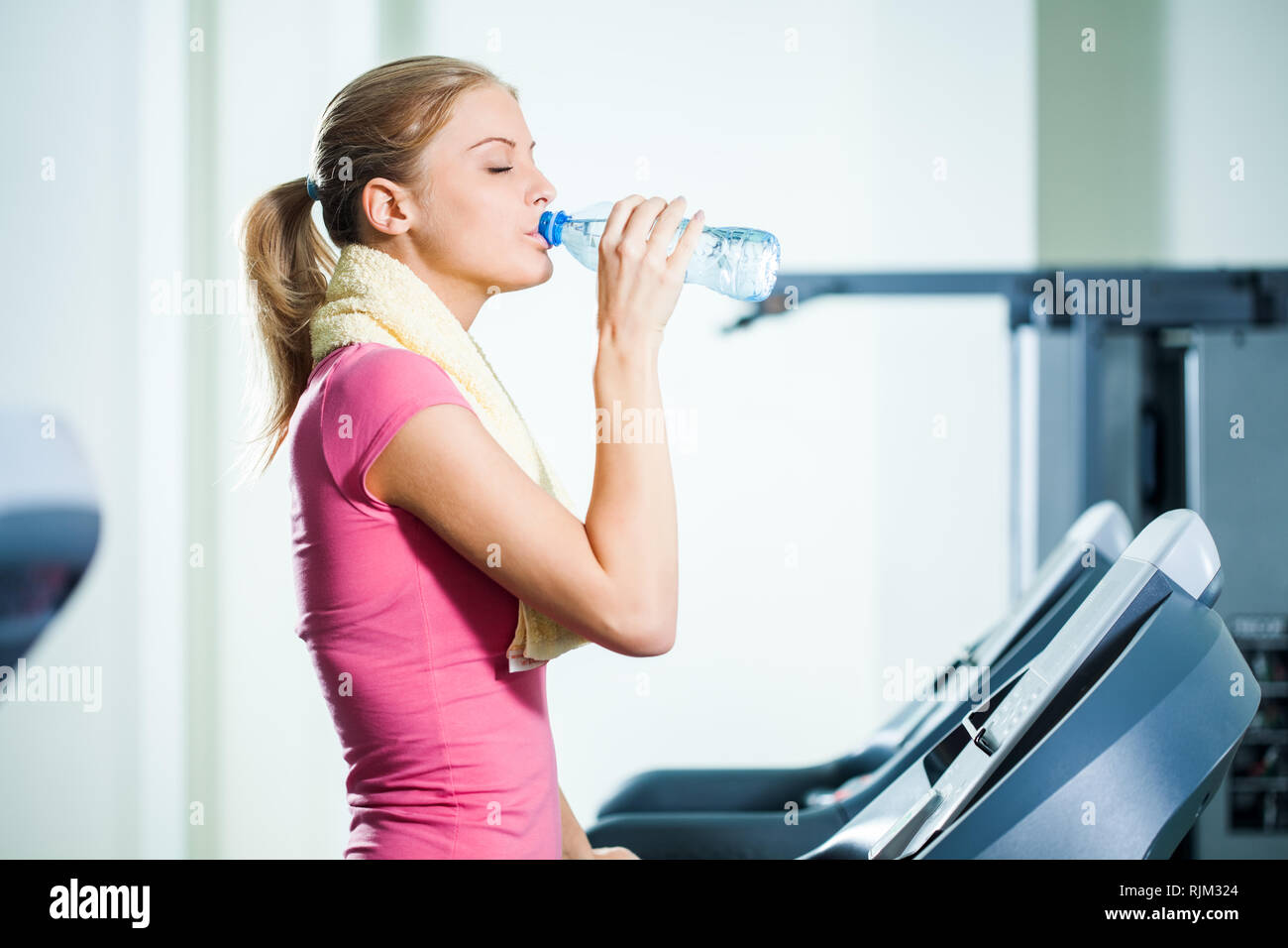 Junge Frau trinkt Wasser während des Trainings in der Turnhalle Stockfoto