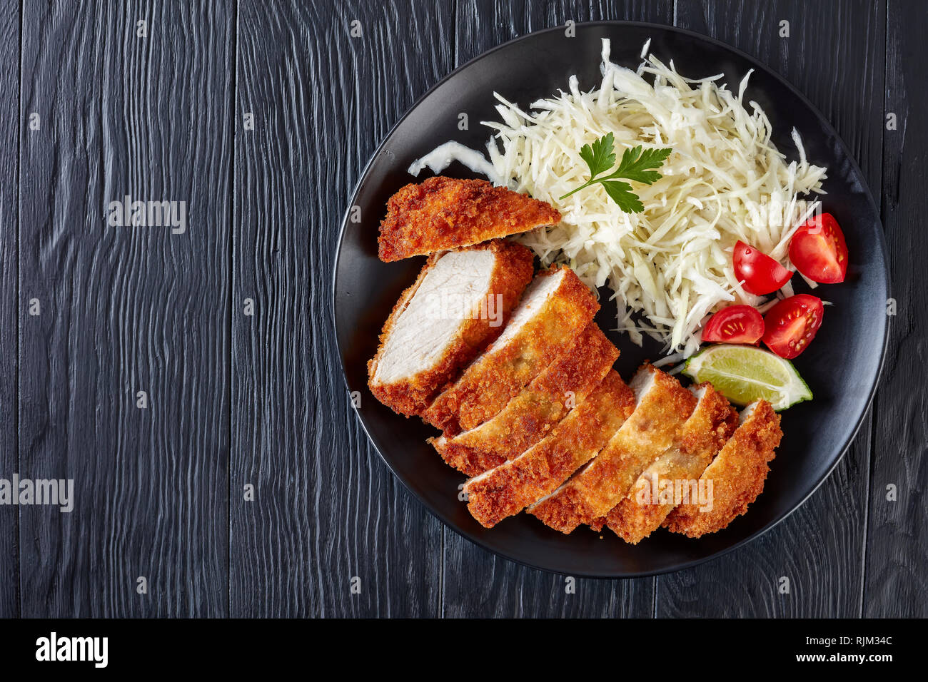 Tonkatsu - panko Panierte frittierte Schweinekotelett. Frittierte Schweinelende Schnitzel mit frischen Kohl Salat, Tomaten und Limettensaft, Scheiben, japanische Küche, Fla Stockfoto