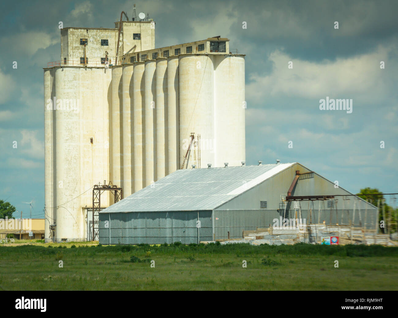 Eine alte industrielle Landwirtschaft Anblick mit alten Silos und neueren metal Scheune in Texas Landschaft Stockfoto