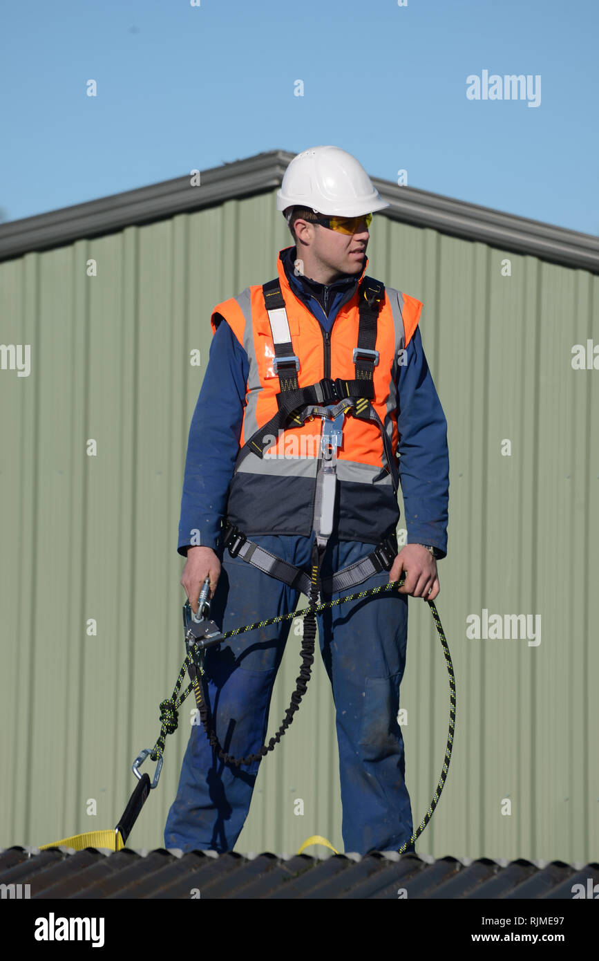 Ein Baumeister tragen eine Sicherheit zu nutzen, während der Arbeit in Höhen wartet auf Anweisungen von der Vorarbeiter Stockfoto