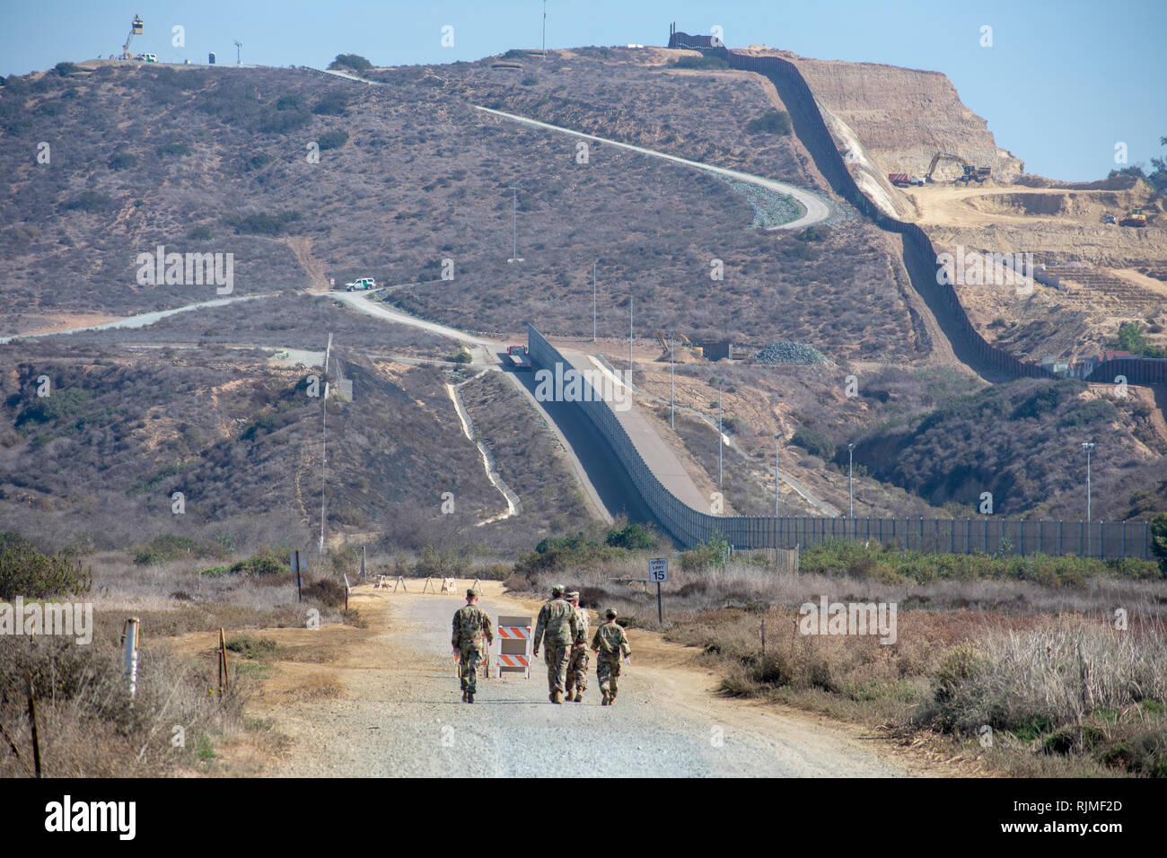 US-Soldaten der Bundeswehr in Grün militärische Tarnung zu Fuß in der Nähe von Double-layered internationale Grenze Mauer zwischen den USA und Mexiko gesichert Stockfoto