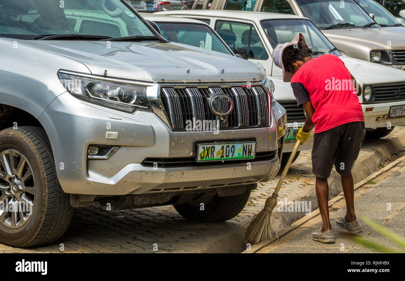 Parys, Südafrika - ein nicht identifizierter schwarzer Mann fegt eine Rinne mit dem Gras Besen Bild im Querformat. Stockfoto