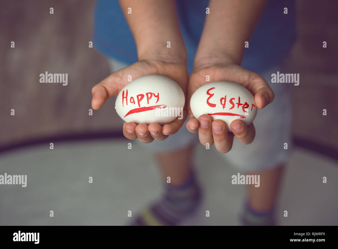 Eier mit der Aufschrift Frohe Ostern das Kind hält in ihren Händen vor Ihm. Stockfoto
