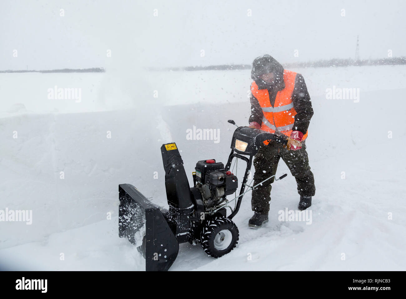 Arbeitnehmer beseitigt Schnee in einem Blizzard mit einem Schneepflug Stockfoto