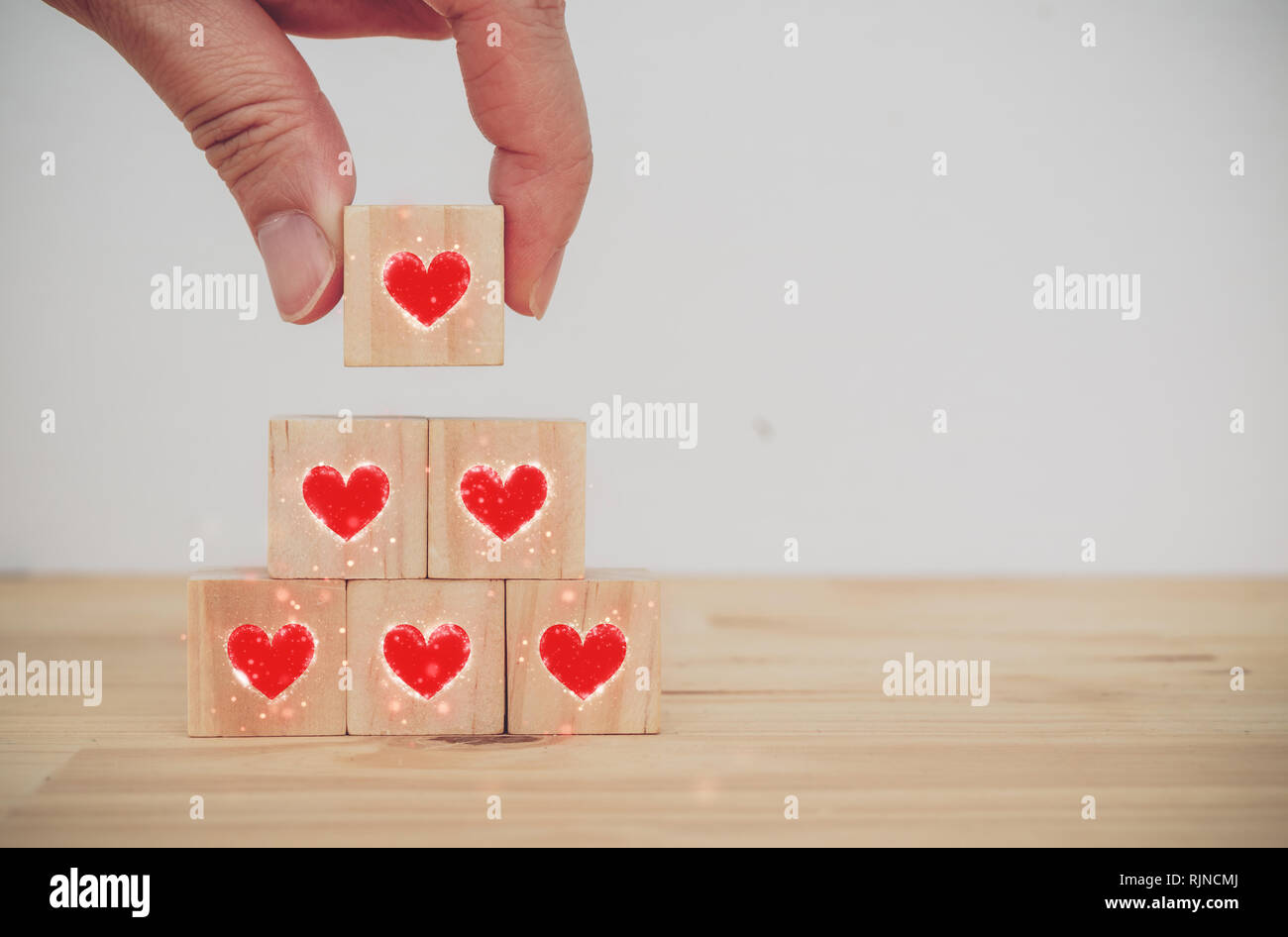 Der Liebe Valentinstag conceptman Hand, die das Herz auf dem Würfel Holz-  die Liebe am Valentinstag zu setzen Stockfotografie - Alamy