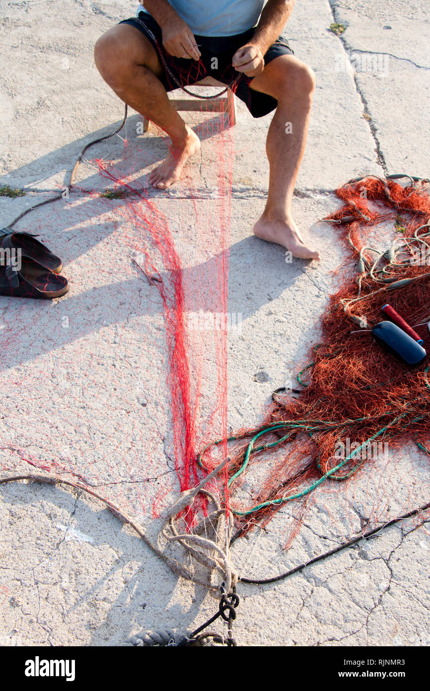 Fischer Instandsetzung fischernetz am Ufer Stockfoto