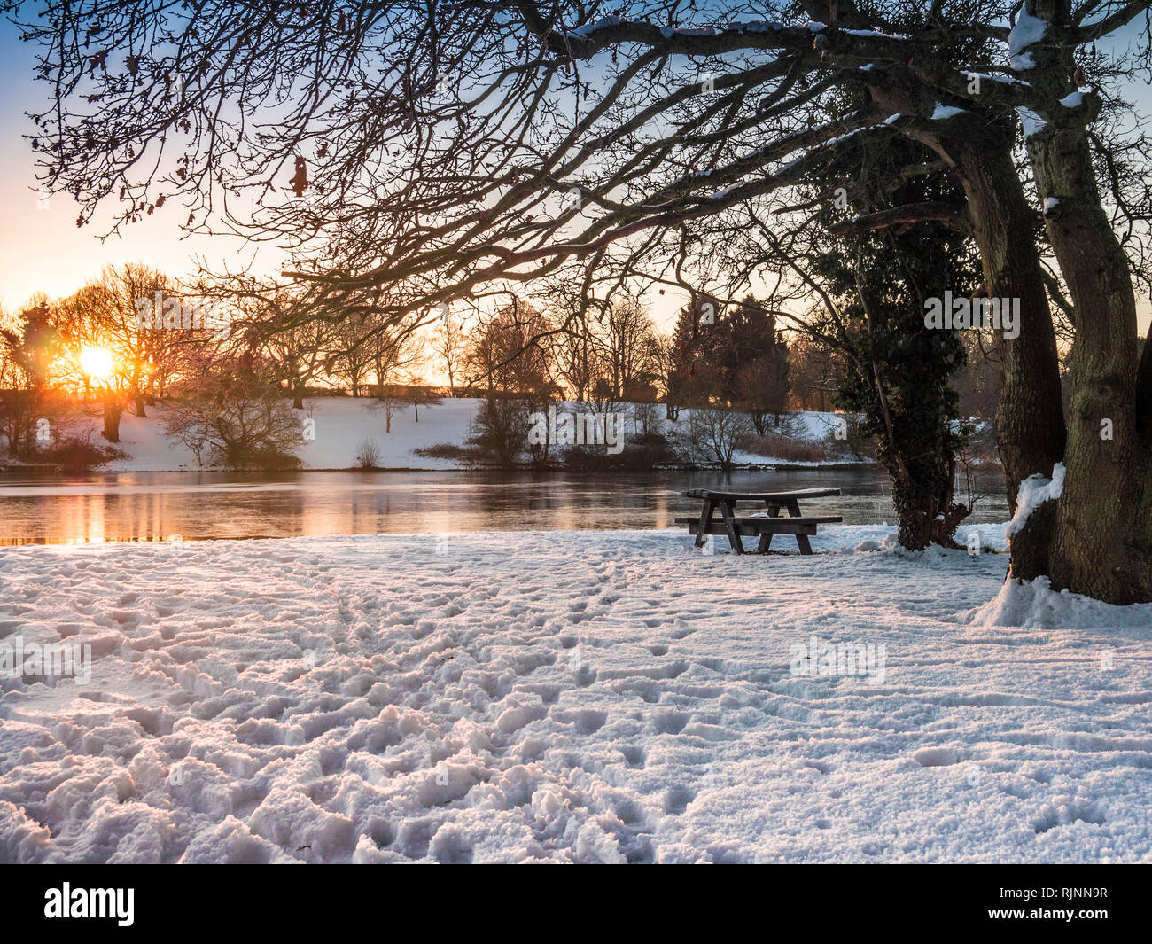Eine schneereiche Winter Sonnenaufgang in Coate Water, Wiltshire. Stockfoto