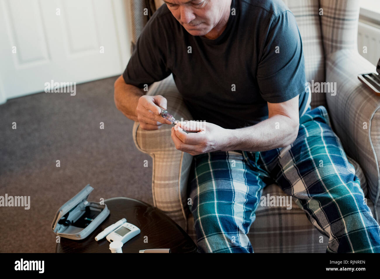 Ältere Diabetiker Mann bereitet sein Insulin pen im Wohnzimmer seines Hauses. Stockfoto