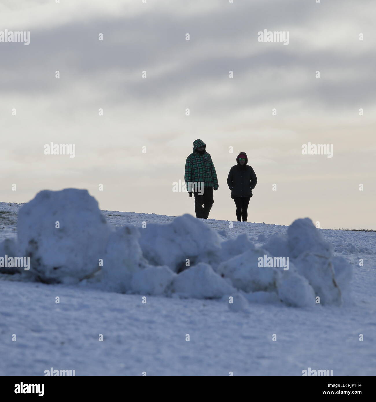 Paar Wandern im Schnee auf die Dunstable Downs, Bedfordshire, England, Großbritannien Stockfoto