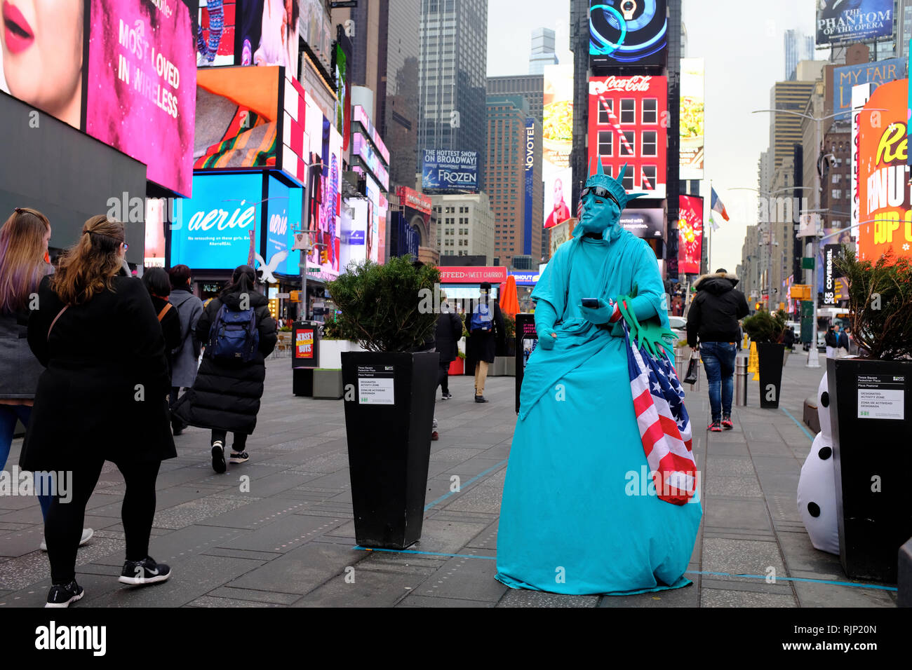 Ein Mann gekleidet, wie die Freiheitsstatue, die eine US-Flagge im Times Square warten auf Touristen Fotos mit ihm Tipps zu erwerben. New York City.NY USA Stockfoto
