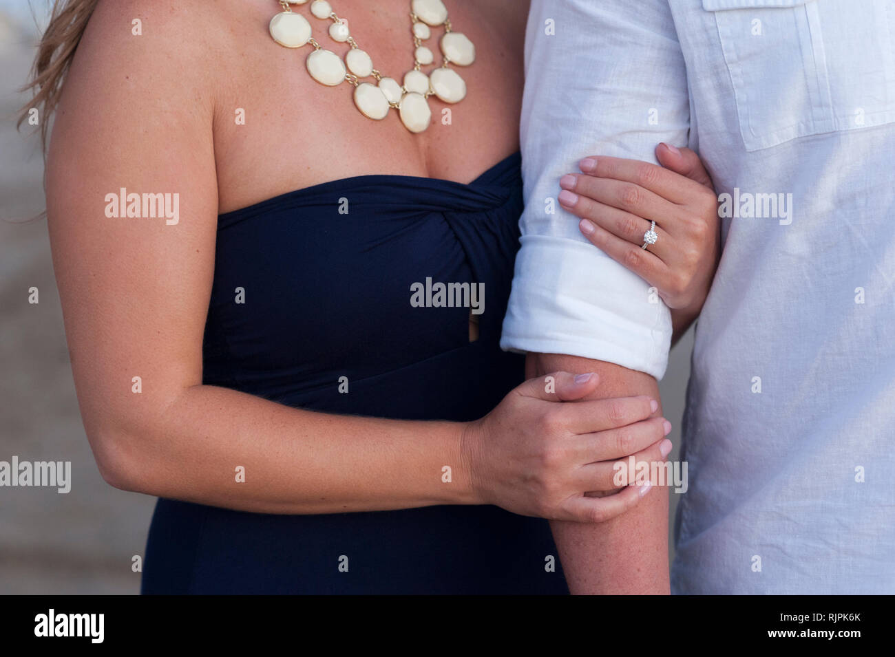 Close-up eine engagierte junge Frau mit Arme ihres Verlobten am Strand bei einem Engagement Fotoshooting. Stockfoto