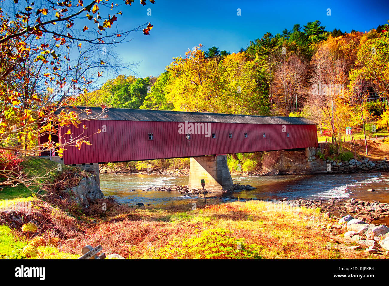 Ein iconic West Cornwall überdachte Brücke überspannt den Fluss Houstanic in Connecticut während der New England im Herbst. Stockfoto