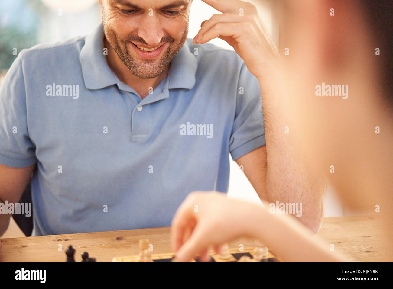 Junge und Vater spielen Schach im Wohnzimmer Tisch, über die Schulter, Nahaufnahme Stockfoto