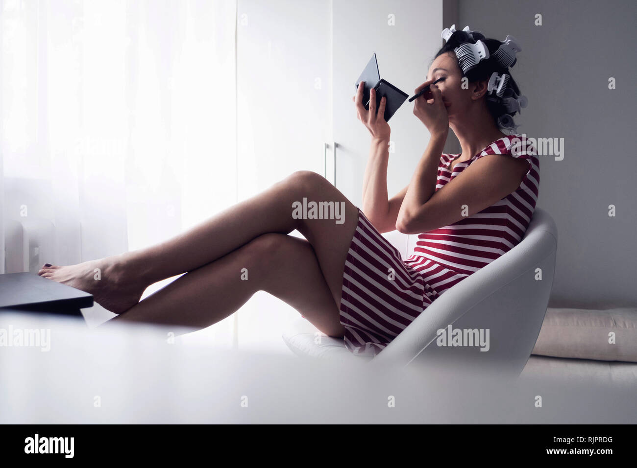 Frau mit Haar-Walzen auf Make-up Stockfoto