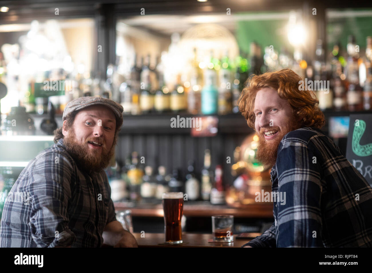 Zwei männliche Kunden, die über ihre Schultern von Bar im traditionellen irischen Public House Stockfoto