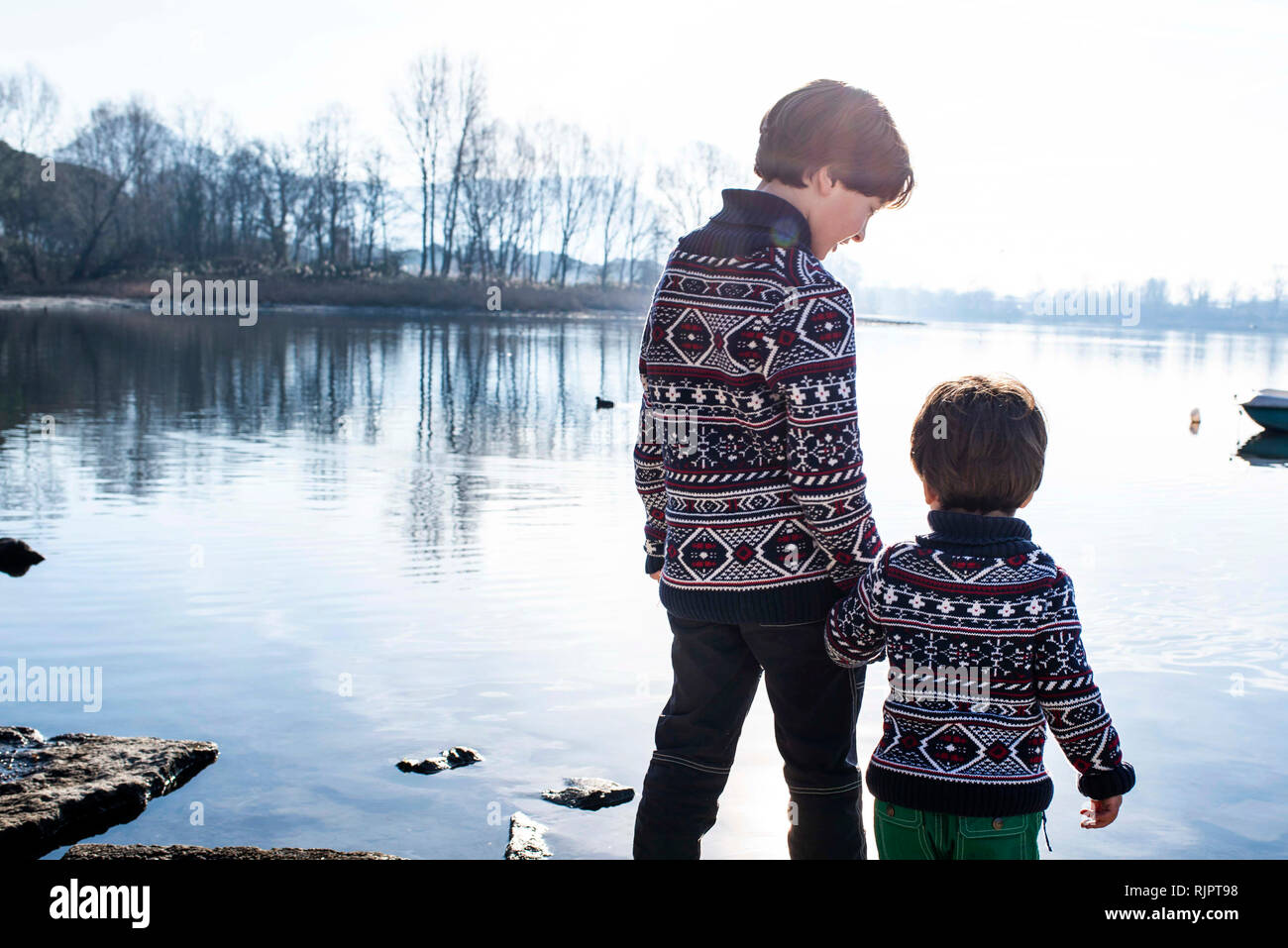 Junge und Kleinkind Bruder in passenden Pullover stehend auf See, Lake Como, Lecco, Lombardei, Italien Stockfoto