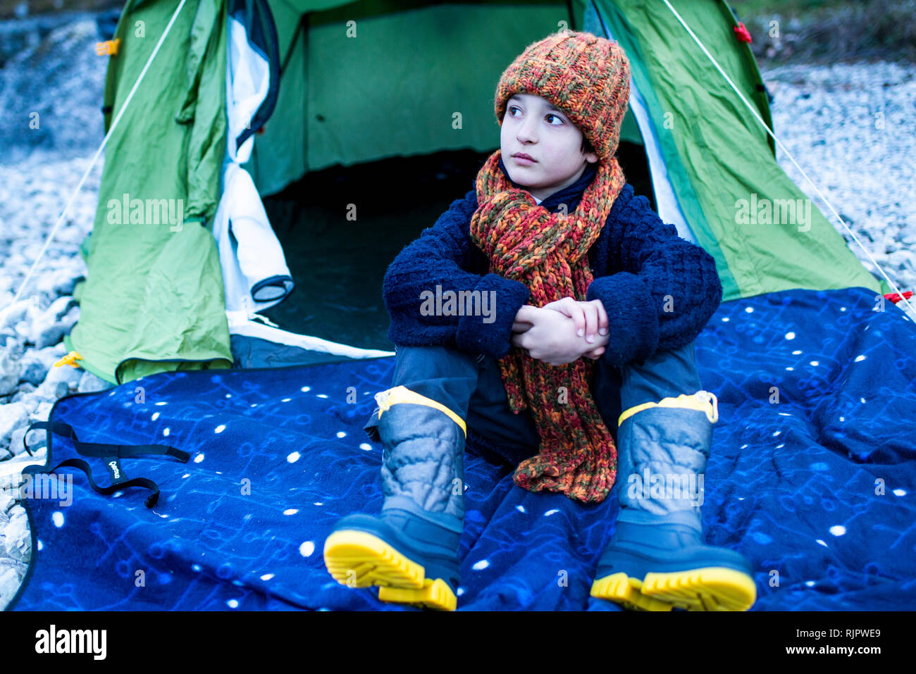 Junge in Strickmütze draußen sitzen Zelt auf See, Comer See, Onno, Lombardei, Italien Stockfoto