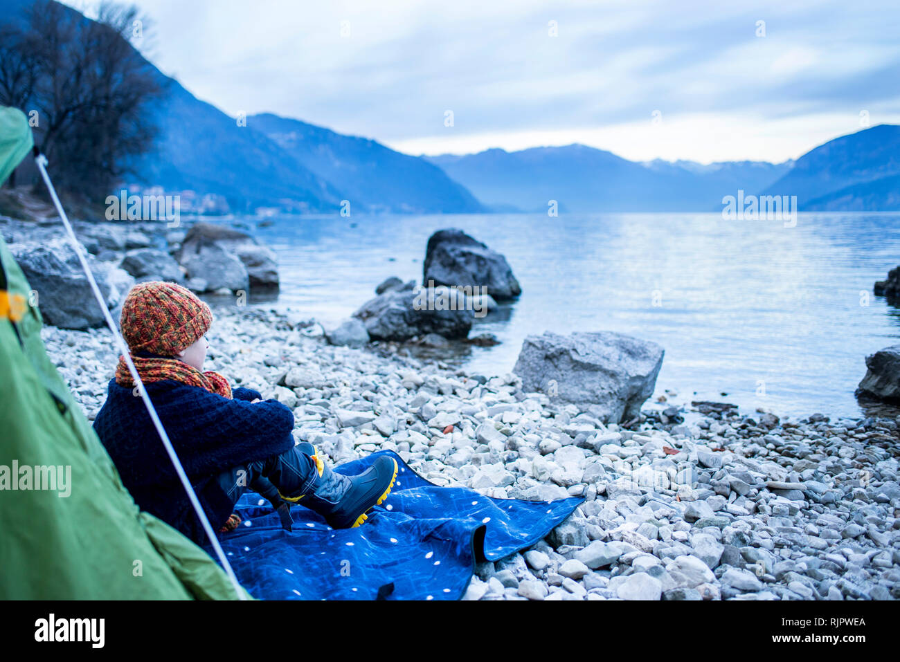 Junge sitzt außerhalb Zelt auf See, Comer See, Onno, Lombardei, Italien Stockfoto