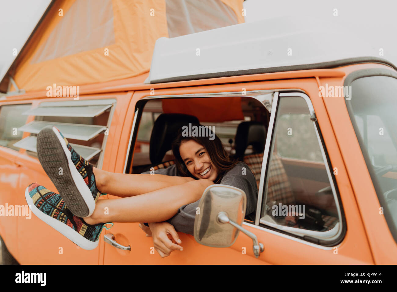Junge Frau mit Beinen durch recreational vehicle Fenster am Strand, Porträt, Jalama, Kalifornien, USA Stockfoto