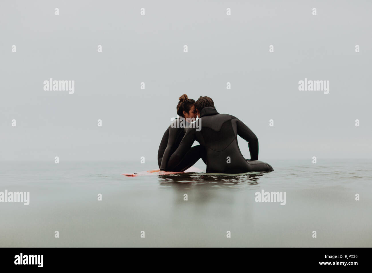 Junge surfen Paar auf Surfboards sitzen in Ruhe misty Sea, Ventura, Kalifornien, USA Stockfoto