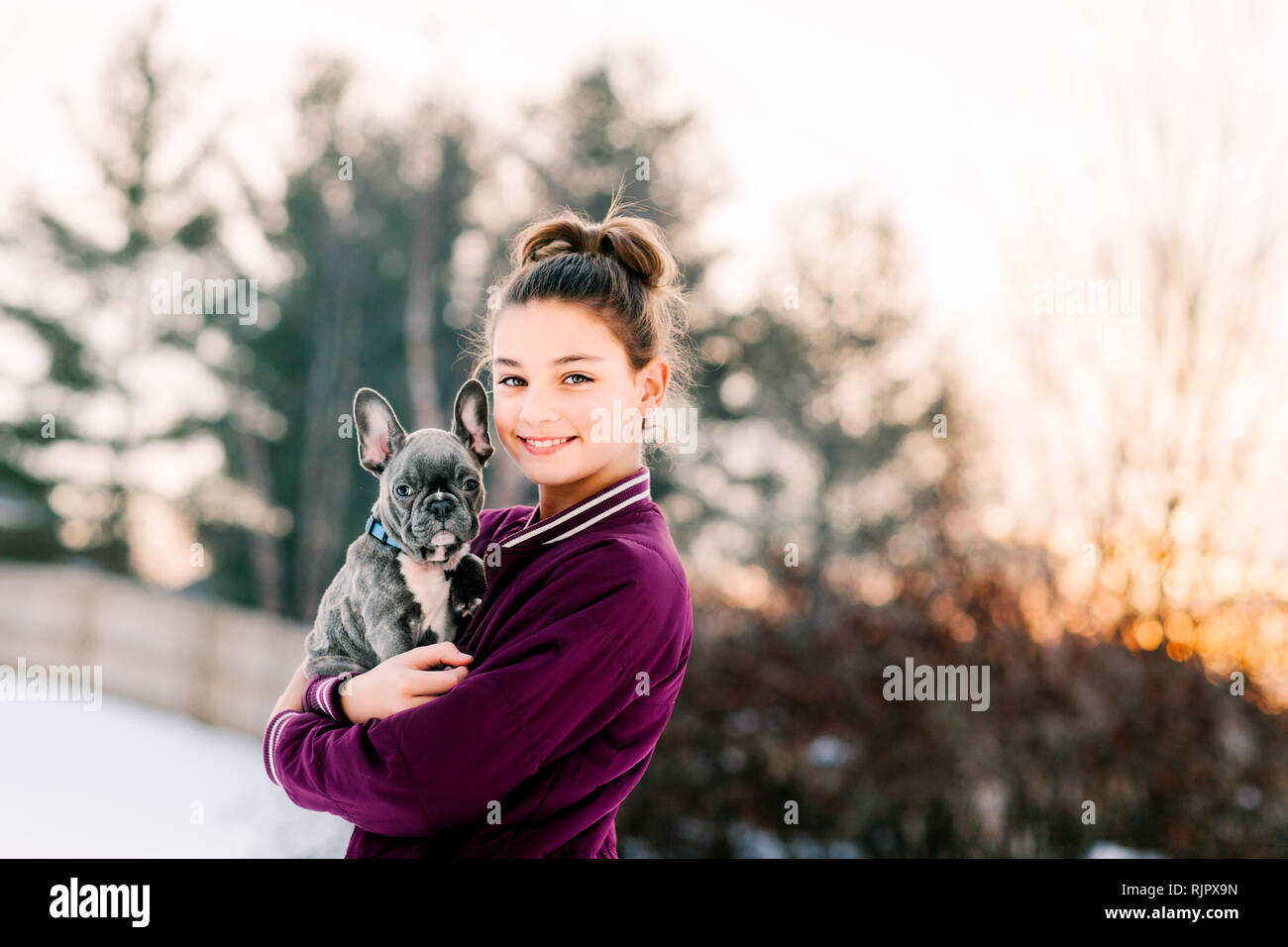 Mädchen umarmt Französisch Bulldog Welpen im Freien Stockfoto