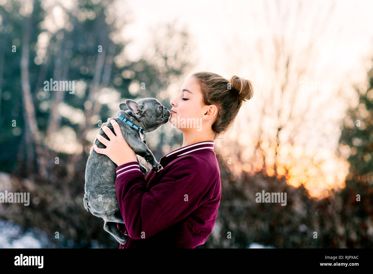 Mädchen küssen Französisch Bulldog Welpen im Freien Stockfoto