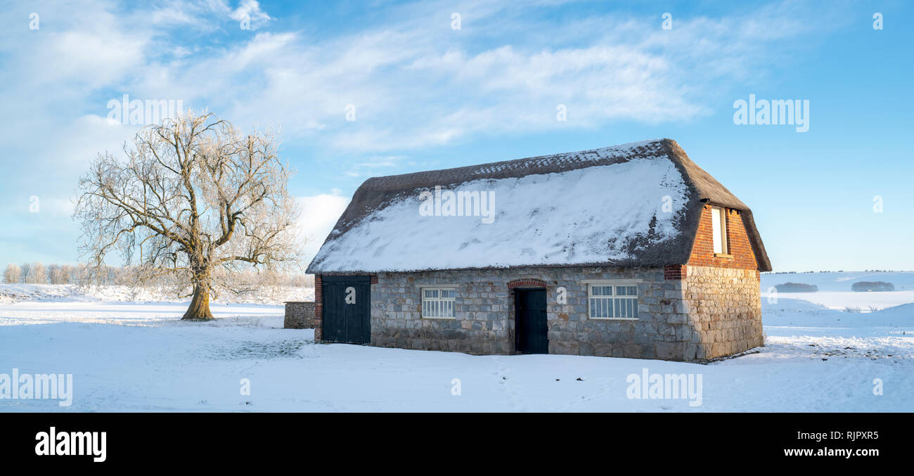 Reetgedeckte Scheune im Winter Schnee bei Sonnenaufgang. Avebury, Wiltshire, England. Panoramablick Stockfoto
