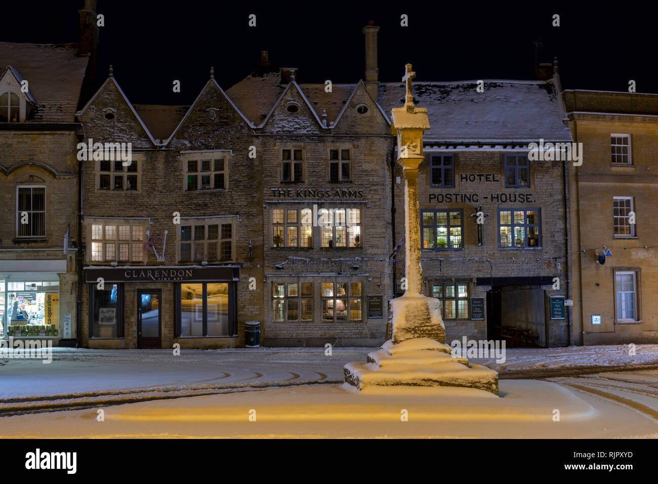 Der Marktplatz Kreuz vor der Kings Arms Pub vor Sonnenaufgang im Winter Schnee. Verstauen auf der Wold, Cotswolds, Gloucestershire, England Stockfoto