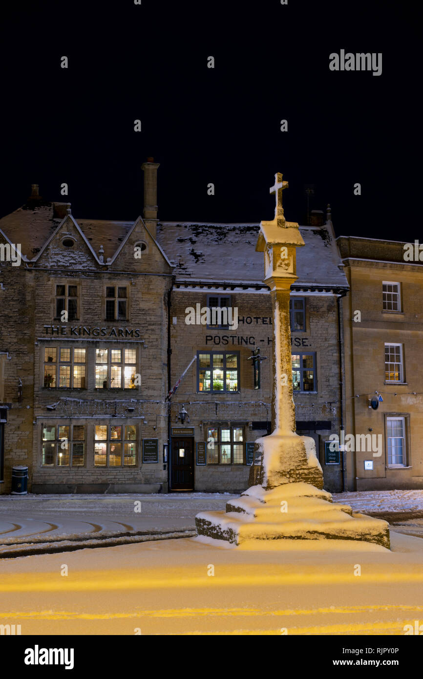 Der Marktplatz Kreuz vor der Kings Arms Pub vor Sonnenaufgang im Winter Schnee. Verstauen auf der Wold, Cotswolds, Gloucestershire, England Stockfoto