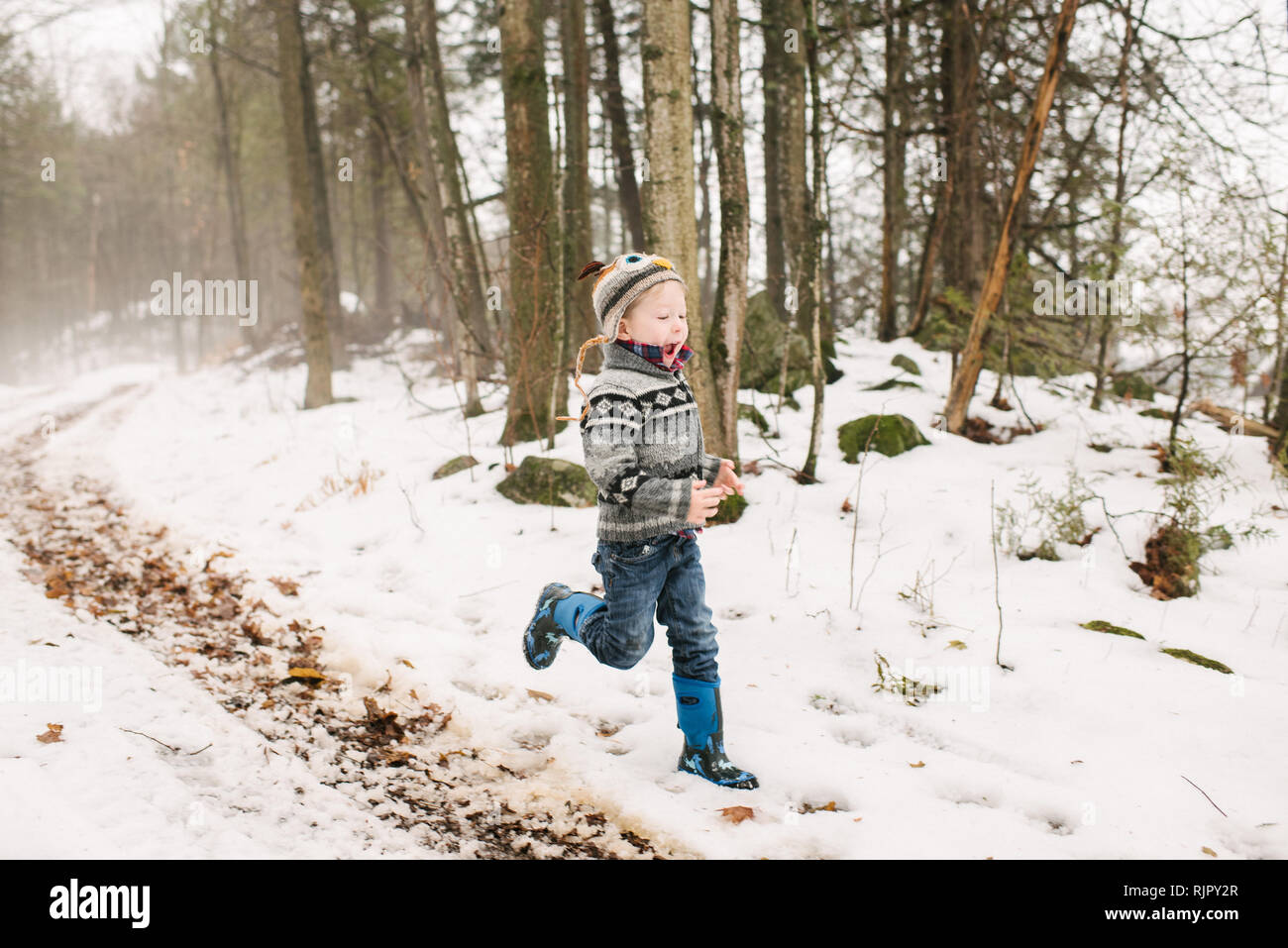 Jungen laufen im Schnee Landschaft durch den Wald Stockfoto