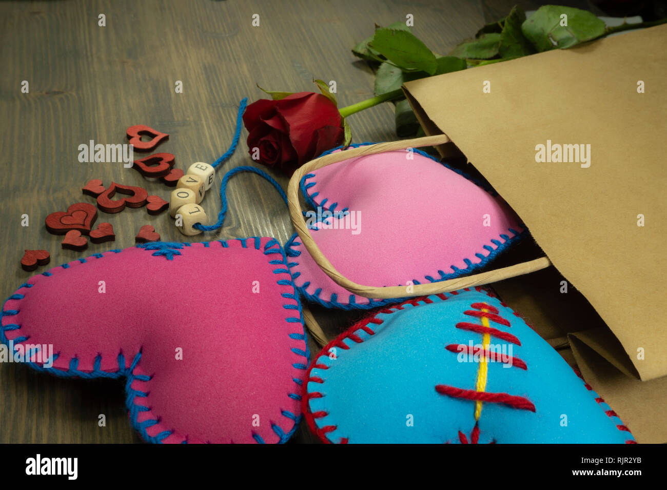 Papiertüte voller Herzen handgemachte Souvenirs, Rose und Liebesbriefe auf rustikalen Holzmöbeln Hintergrund. Liebe, Beziehung, Valentinstag, gebrochene Herzen anhand von quantitativen Simulatio Stockfoto