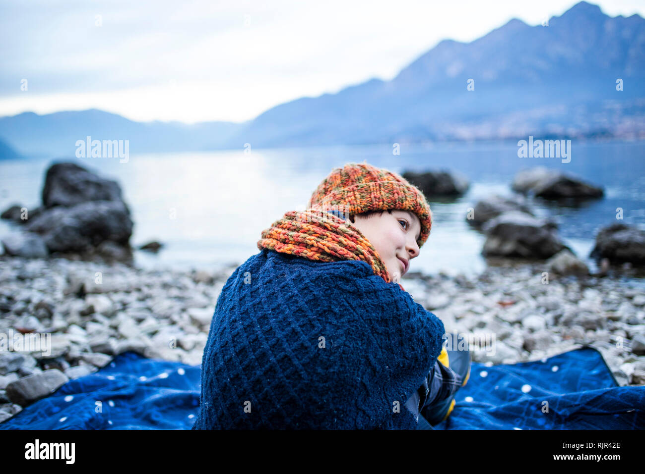 Junge sitzt auf der Decke auf See, Comer See, Onno, Lombardei, Italien Stockfoto