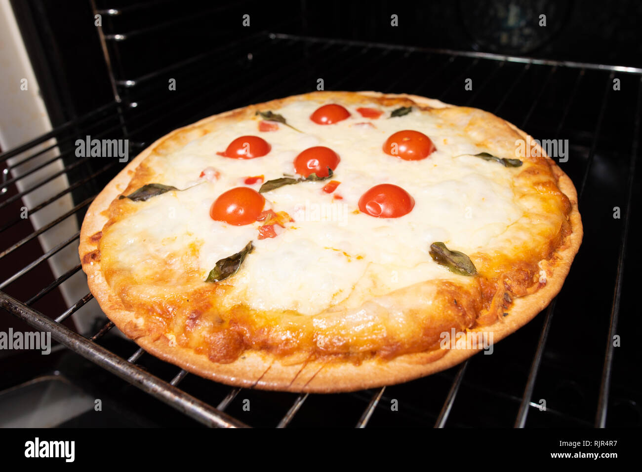 Pizza backen closeup mit Tomaten und Käse aus dem Ofen Stockfoto