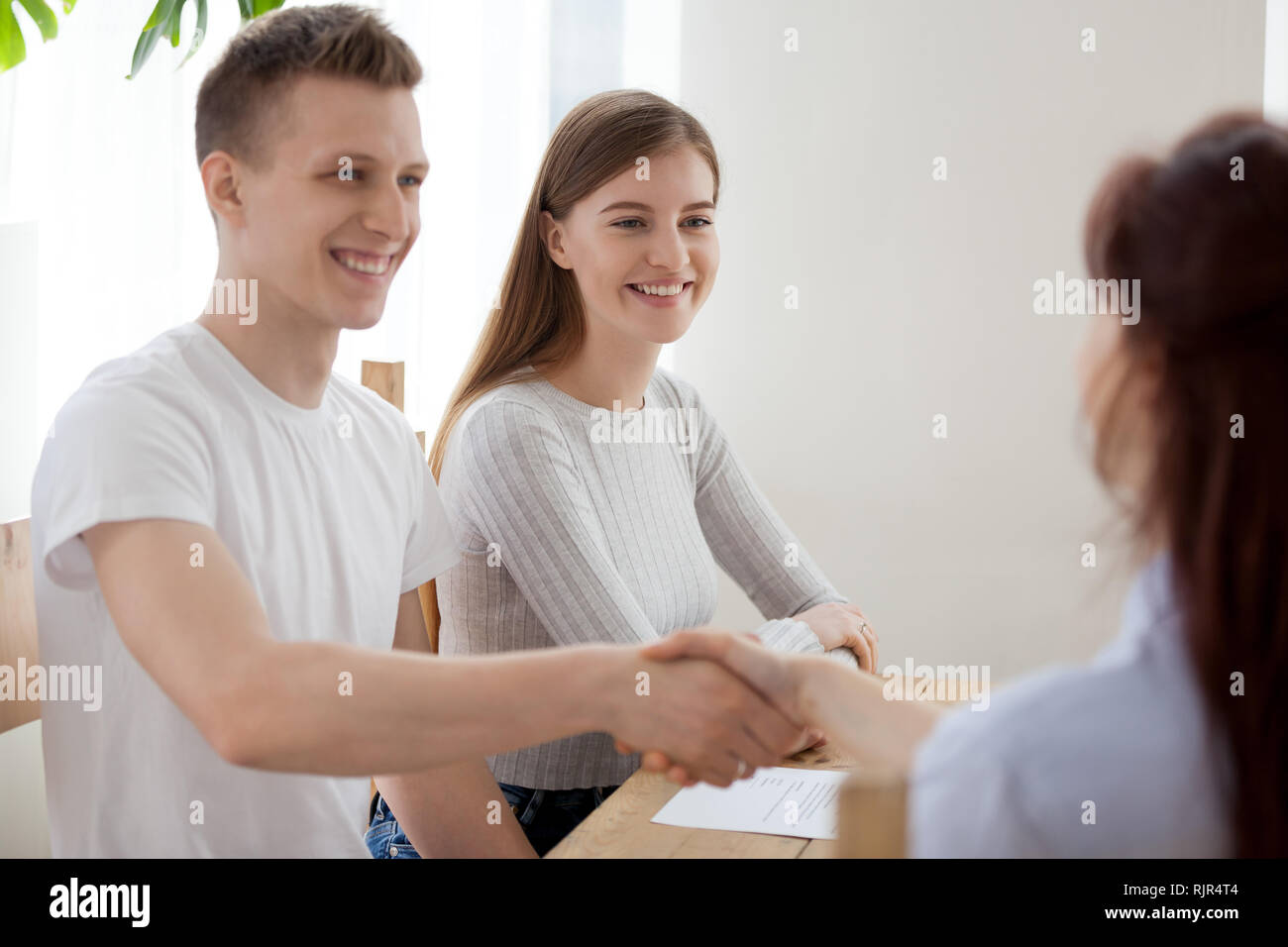 Glückliches Paar clients handshaking Versicherer Bank worker Advisor bei Konferenz Stockfoto