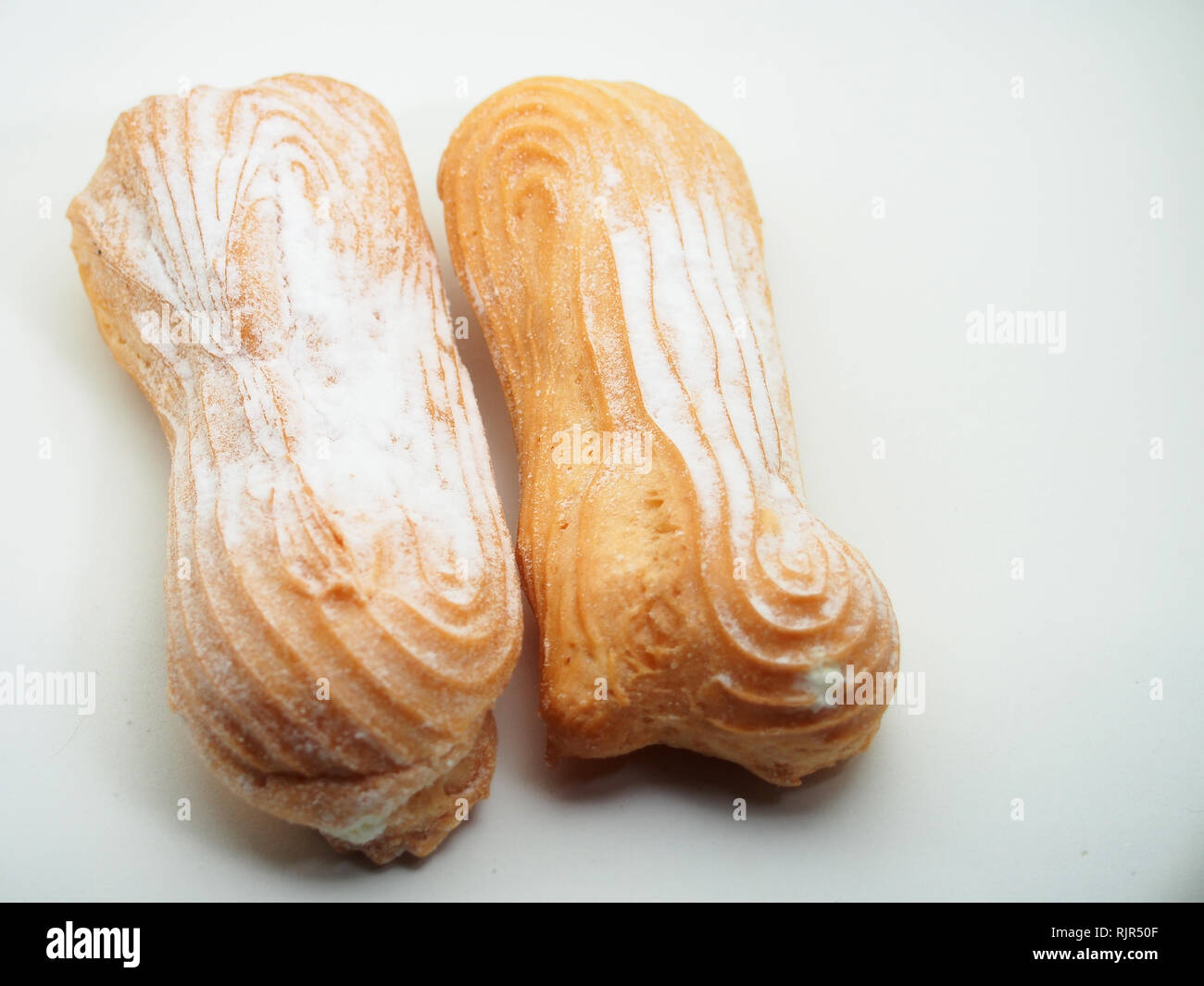 Eclair Kuchen bestreut mit Puderzucker auf einem weißen Hintergrund. Still-Leben. Stockfoto