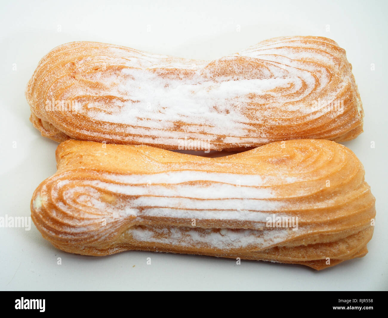 Eclair Kuchen bestreut mit Puderzucker auf einem weißen Hintergrund. Still-Leben. Stockfoto