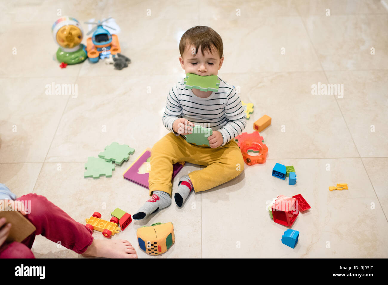 Baby Boy und Bruder mit Spielzeug spielen auf dem Boden Stockfoto