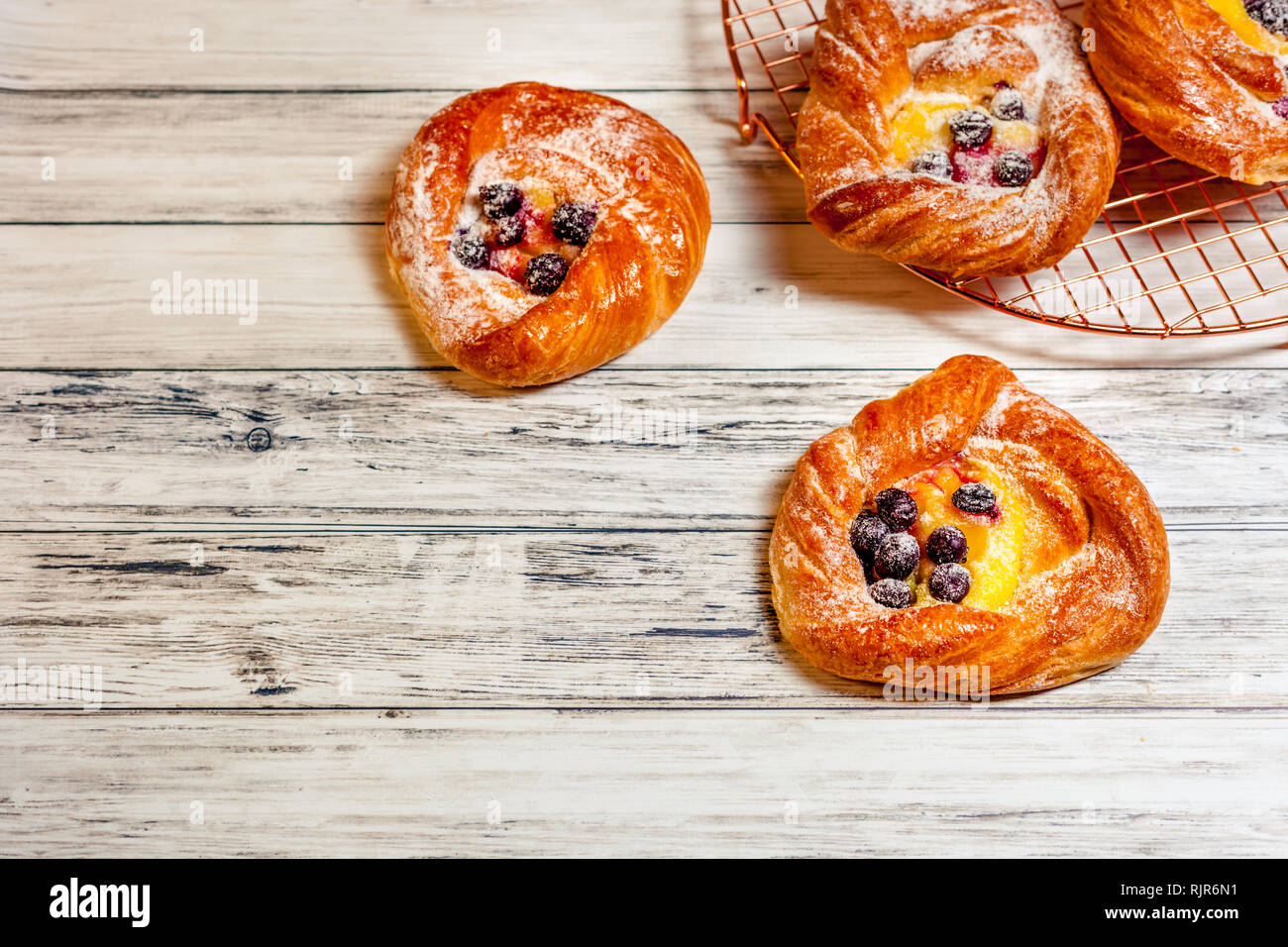 Blick von oben auf die goldenen Käse dänische Pasteten mit Brombeeren und Pulver Zucker Stockfoto