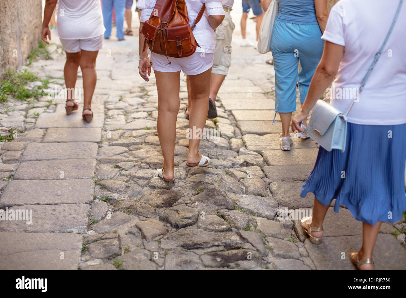 Eine Menge Leute sind zu Fuß entlang einer alten Straße mit Kopfsteinpflaster. Italien, Kalabrien, Tropea. Sightseeing Gruppe. Ansicht von hinten Stockfoto