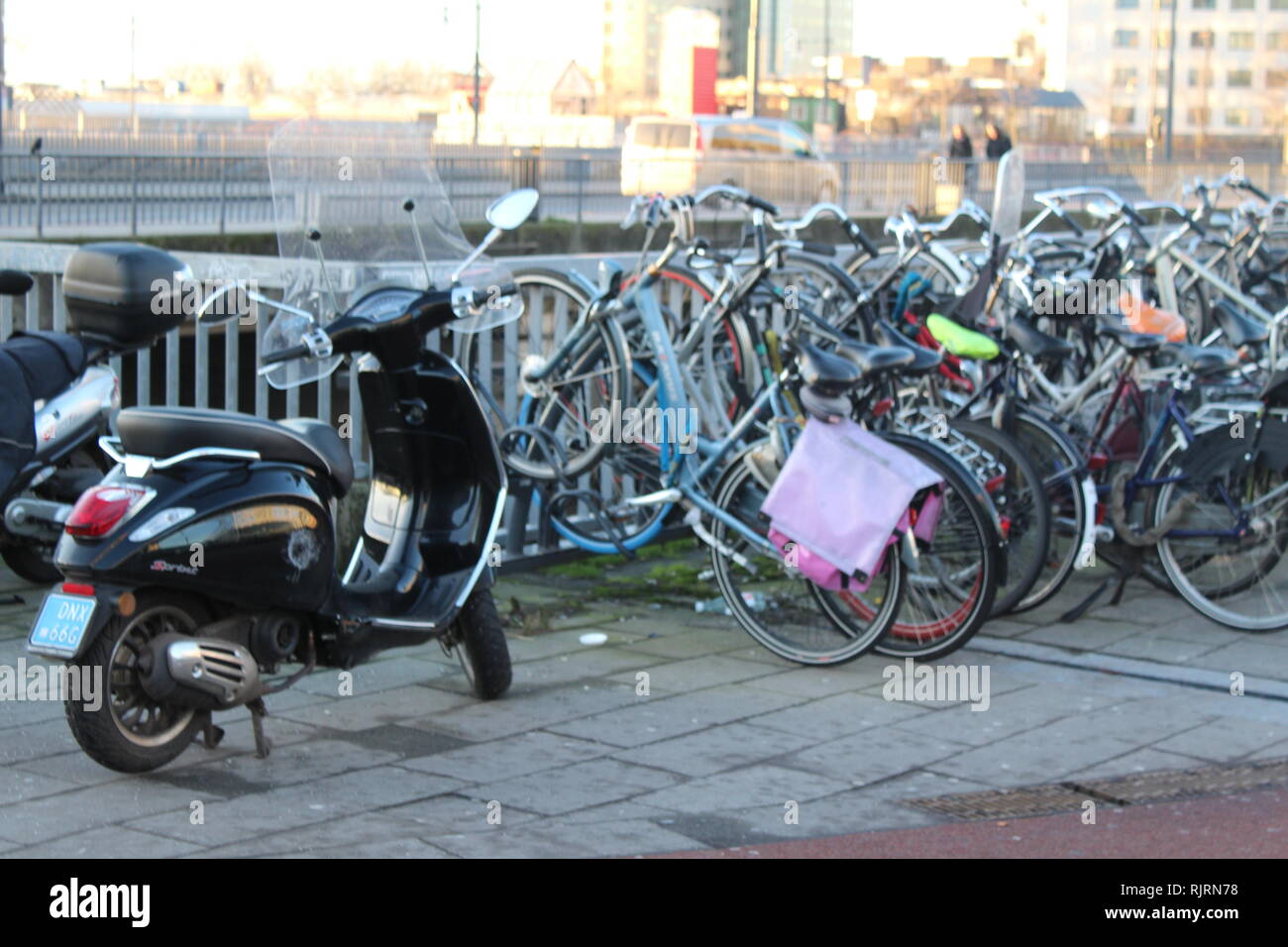 Schwarz moped Roller geparkt Neben Fahrrädern in Amsterdam, Niederlande Stockfoto
