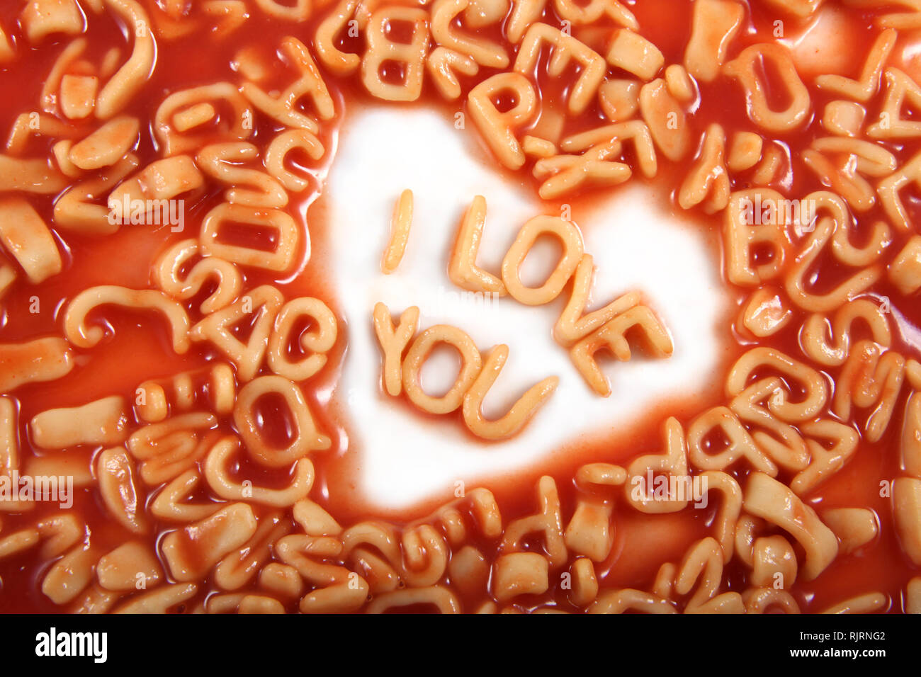 Ich liebe dich Text geschrieben in Alphabetti Spaghetti Nudeln geformt Briefe mit Tomatensauce um ihn herum. Stockfoto
