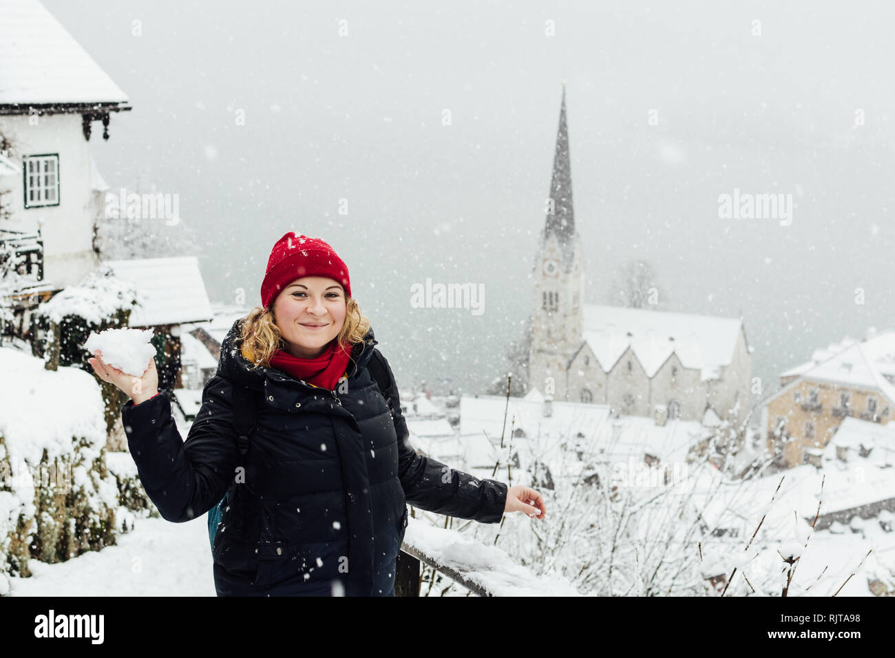 Frau in Red Hat eine Schneeballschlacht in Hallstatt Altstadt während der schneesturm in, Österreich Stockfoto